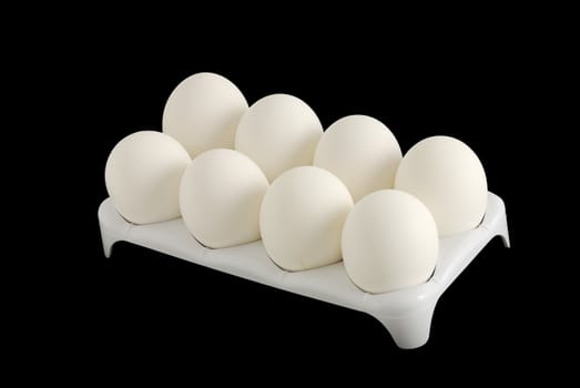 Eight white eggs in carton isolated on black background