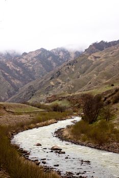 A curved river which flows in a valley on a mountainous background
