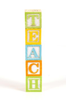 Childrens colorful blocks spell the word teach.