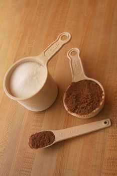 Measuring cups with cocoa, brown and white sugar.