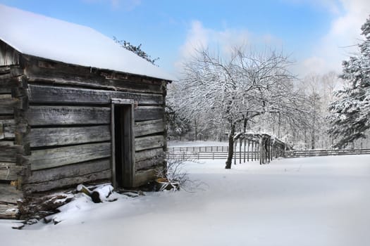 An old log cabin in winter with blue sky.