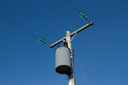 Terminal electricity post with apparatus container and cables against a blue sky.