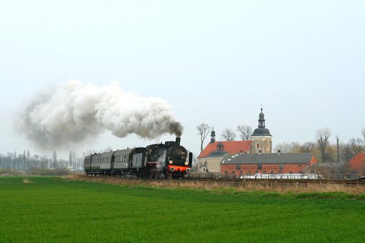 Steam retro train passing the village