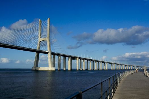 Sunlight over Lisbon's Vasco da Gama bridge and nearby pier