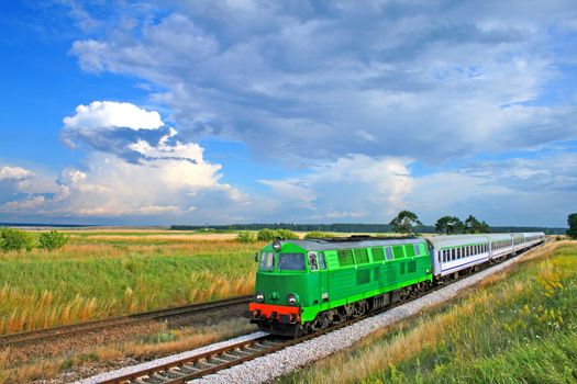 Intercity train passing the countryside with colorful sky over