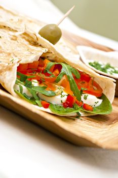 wheat wrap with olive filled with tomato, mozarello, bell pepper and salad. Some dip.