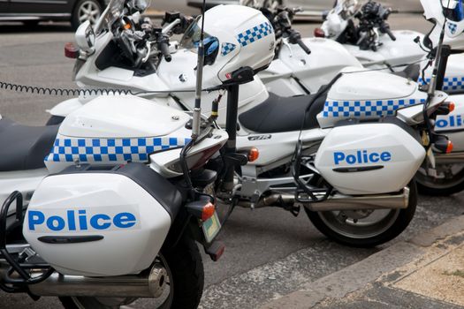 Police motorcycles, parked with helmets on post at rear.