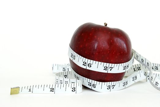 A red apple with a measuring tape wrapped around it for the concept of healthy eating.