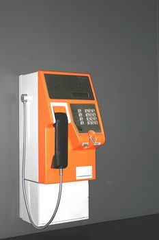 Image of an orange public payphone.