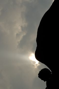 black angel silhouette, dark grey clouds and white sun