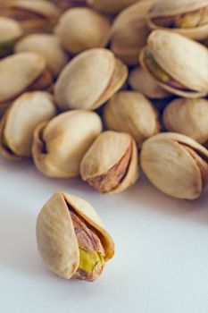 Salted pistachios  on white background, one in foreground, distance blur