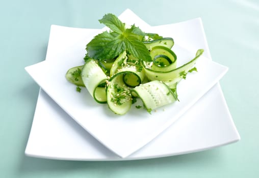 Salad of sliced green cucumbers with herbs and sesame seeds with mint leaves