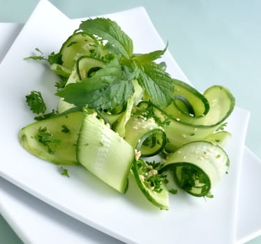 Salad of sliced green cucumbers with herbs and sesame seeds with mint leaves