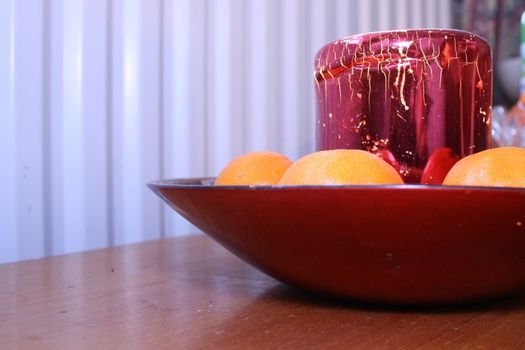 festive candle and clementines in a red glass bowl