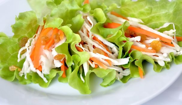 Salad with cabbage, carrots and raisins, wrapped in lettuce leaves