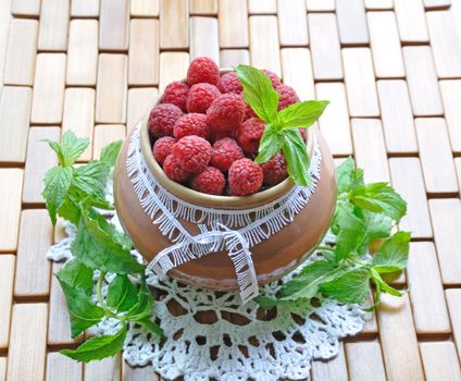 Raspberries in a jar on a knitted cloth with mint leaves
