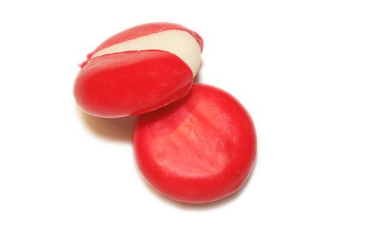mini edam cheeses covered in red wax coating over a white background