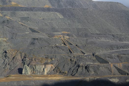 A hillside of slate waste from a quarry, winding houses and industrial inclines are situated on the hillside.