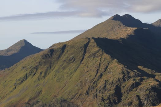 Mountainous landscape with high flanks leading to a ridge line with a wintery sky with cloud.