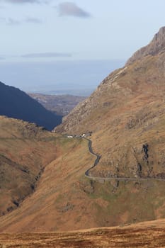 A mountainous landscape with high flanks containing a road that leads to a mountain pass.