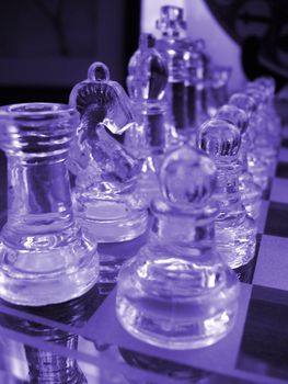 glass chess set game with a engraved glass playing board coloured blue the knight is the focal poin