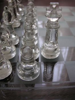 glass chess set game with a engraved glass playing board  the front pawn is the focal poin