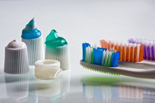 Colorful toothpaste squeezed onto their caps with toothbrushes and floss