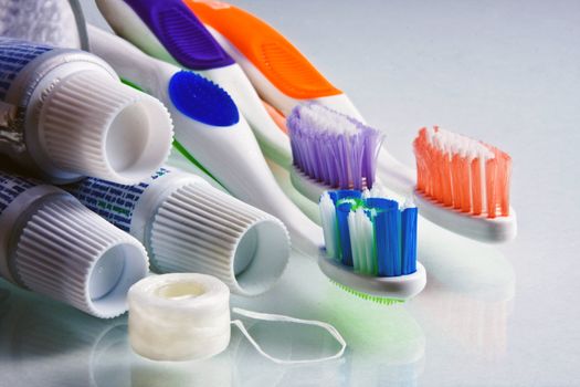 Toothpaste tubes with various colored  toothbrushes and floss