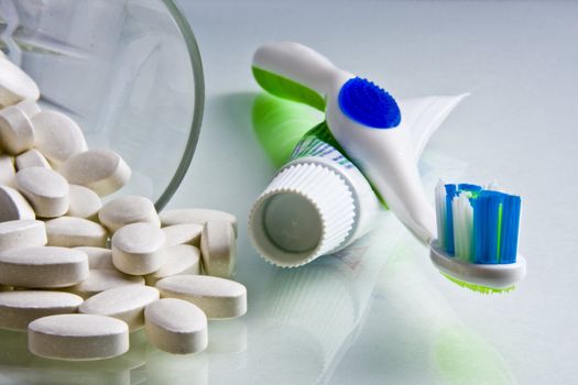 Calcium tablets spilled from a glass with toothpaste and toothbrush beside them