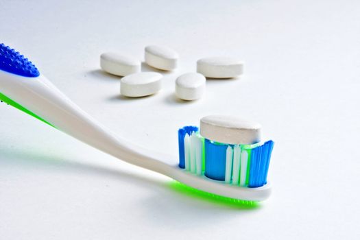 Calcium tablet resting on toothbrush bristles with other tablets in background
