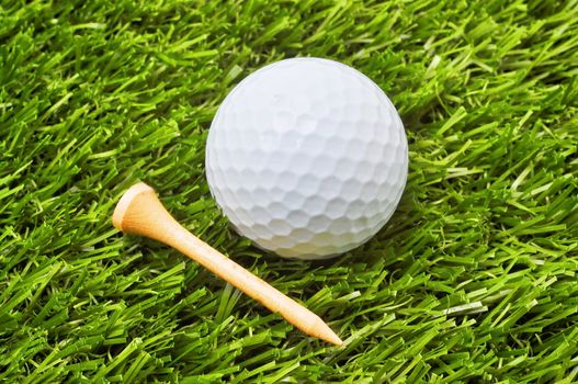 Closeup of golf ball and tee on grass.
