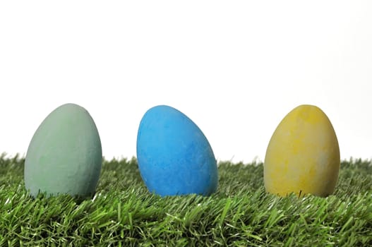 Three Easter eggs on grass on white background.