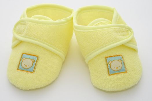 babies first pair of shoes in a yellow towelling material