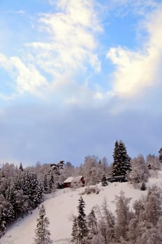 Dramatic clouds and small houses in winter woods
