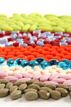 Different colored and shaped pills lined up on a white background.