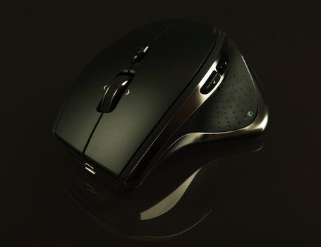 Stylish computer mouse on a glass table over a black background