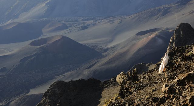 The girl at craters of Haleakala. Early morning, a smoke, wrapped up in white the girl in rising sun beams costs at edge of breakage against craters.