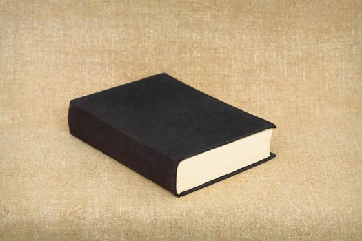 One old big black book on brown canvas background
