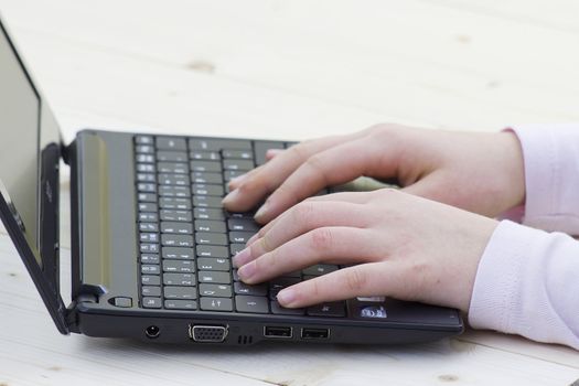 child hands typing on a keyboard of laptop 
