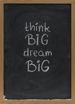 think big, dream big slogan handwritten with white chalk on blackboard with erase smudges