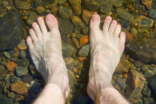 Bare feet on shoal of pure lake