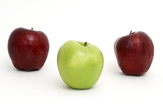 A green apple leads the other two red ones.
