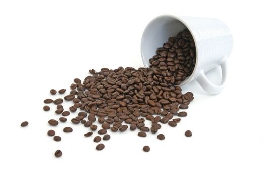 A cup of coffee beans has tipped over and spilled out.