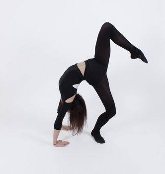 Young gymnast in black in studio with background