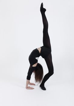 Young gymnast in black in studio with background