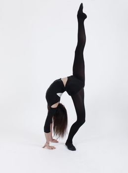 Young gymnast in black in studio with background