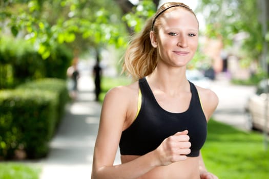 Portrait of a young woman smiling and jogging in the park against blur background
