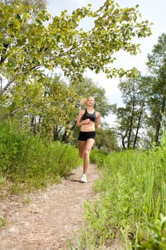 Young woman jogging outdoors in summer on trail