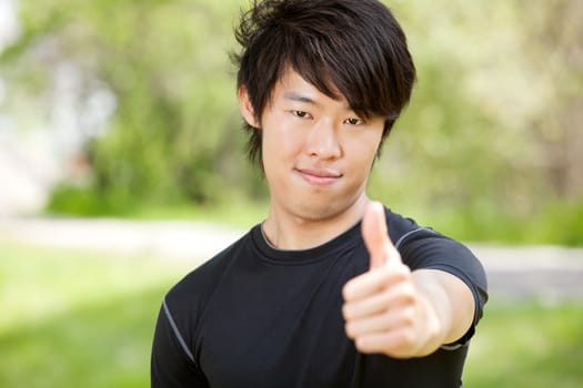 Portrait of a man showing thumbs-up sign against blur background