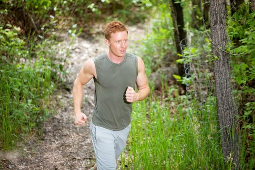 Handsome man running in forest against blur background